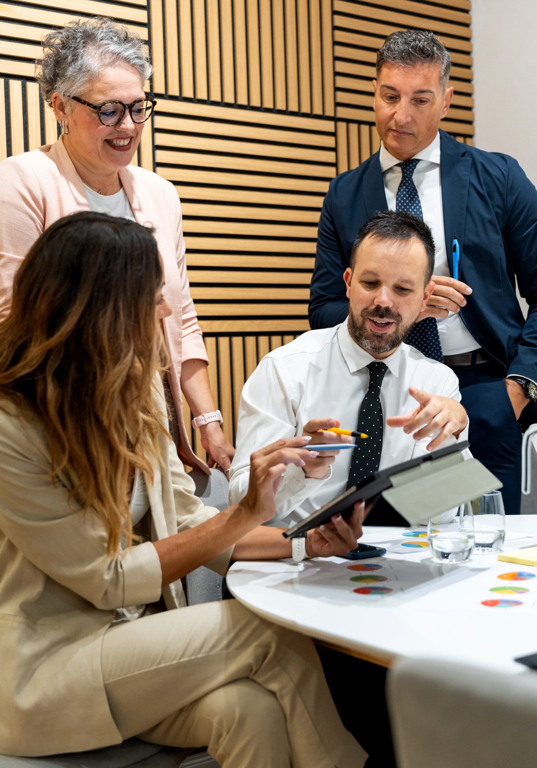 Business professionals discussing strategy during a meeting, utilizing a digital tablet to review data and enhance teamwork