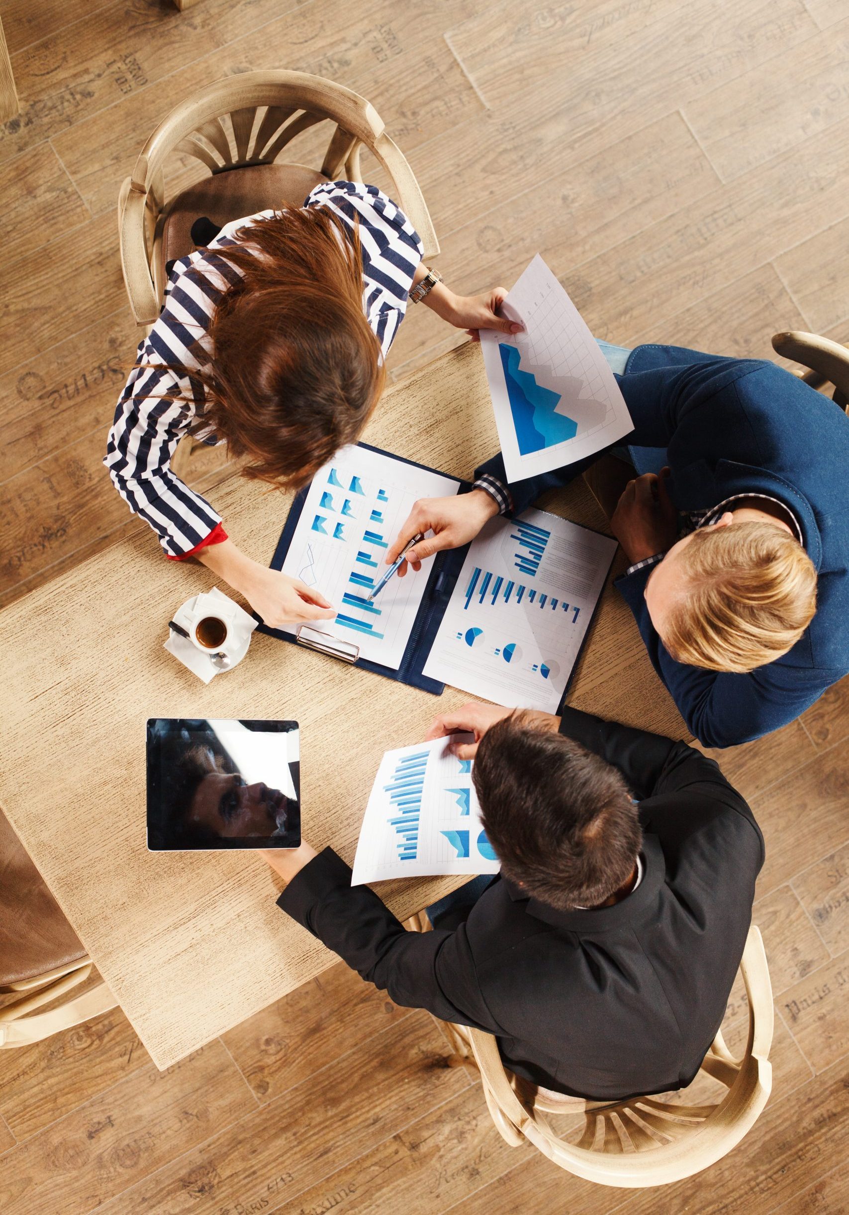 Small group of business people at a meeting in a cafe. Selective focus on papers on table.